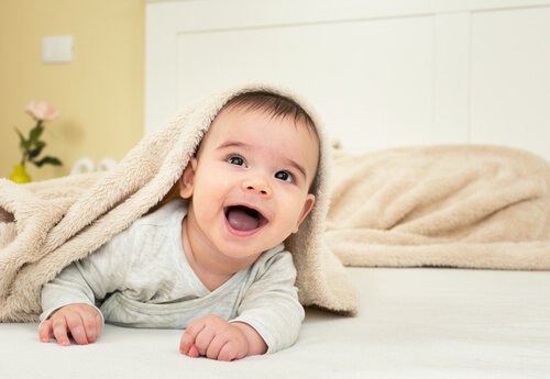 Baby lachend onder een deken