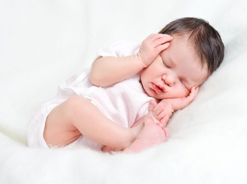Slapende baby met handjes op hoofd