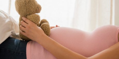 Knuffelbeer op de buik van een zwangere vrouw 