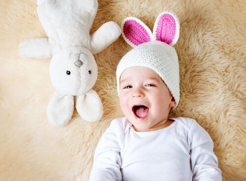 Baby en konijn liggen op een kleed