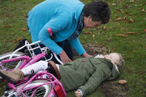 Meisje ligt op de grond onder fiets