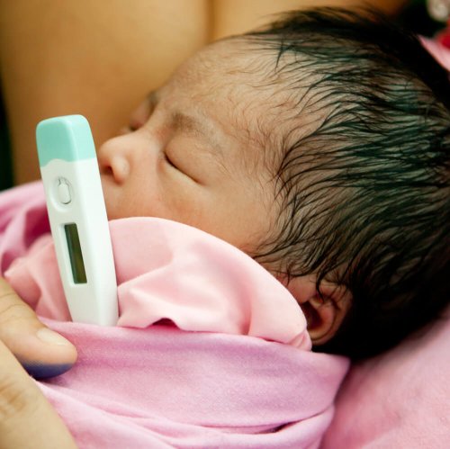 Koortsige baby met thermometer