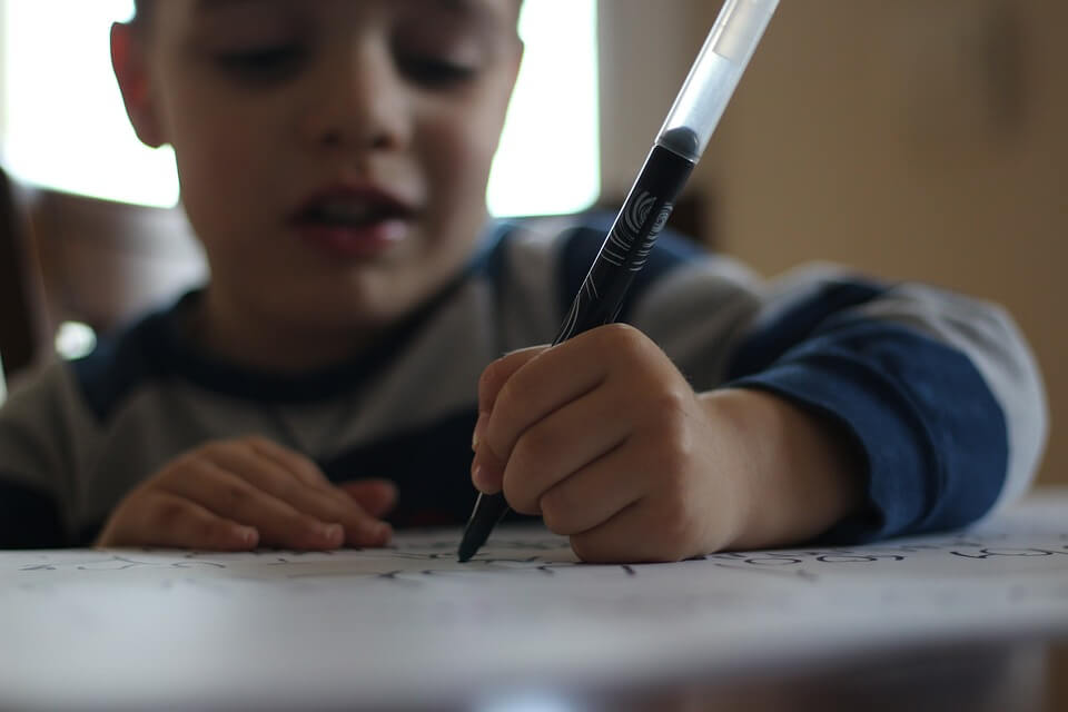 Kind schrijft met een stift