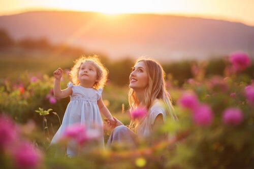 Lachende moeder en dochter tussen de bloemen