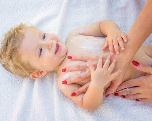 Moeder smeert lotion op baby