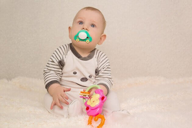 Baby met een speen en een speeltje