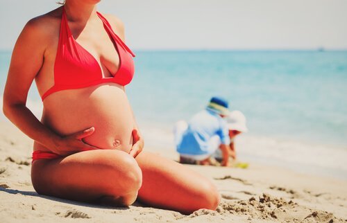 Zwangere vrouw zit op het strand