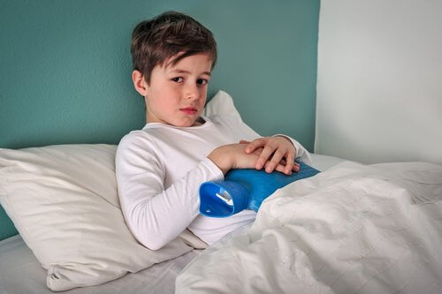 Jongetje in bed met een warme kruik op zijn buik