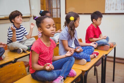 Kinderen mediteren op hun tafel in de klas