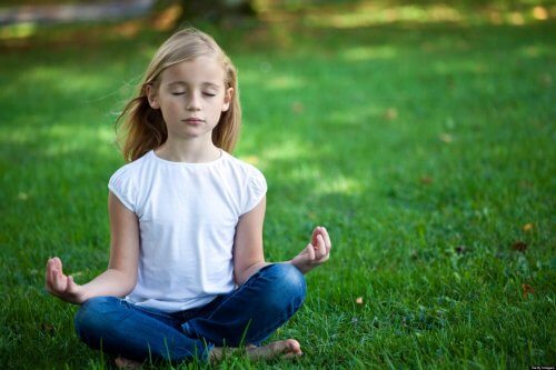 Meisje zit in het gras te mediteren