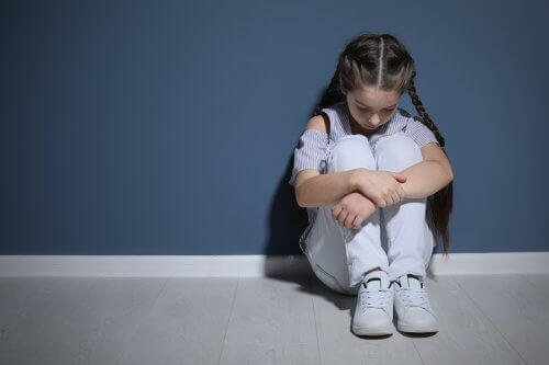 verdrietig meisje zit tegen een muur