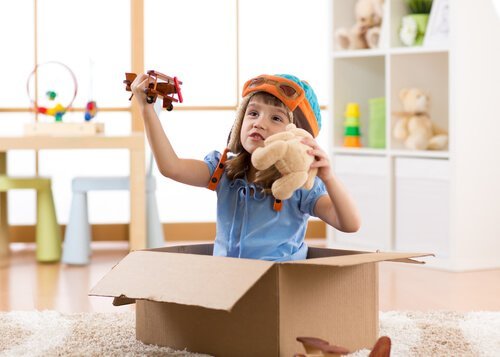 Kind speelt met speelgoed en kartonnen doos