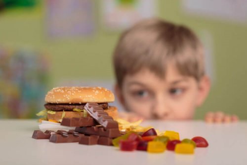 Jongen kijkt naar hamburger en snoep