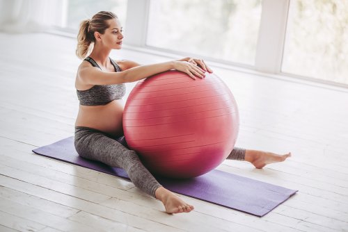 Vrouw met een oefenbal op een yogamat