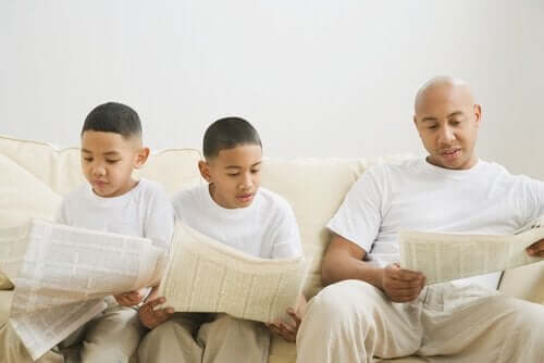 Vader leest de krant en zoons imiteren gedrag