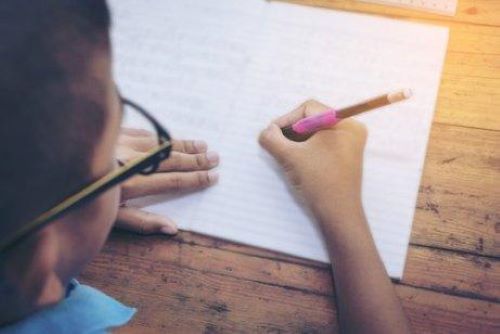 Jongen schrijft in een schrift