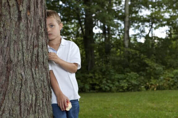 Jongen verstopt zich achter een boom