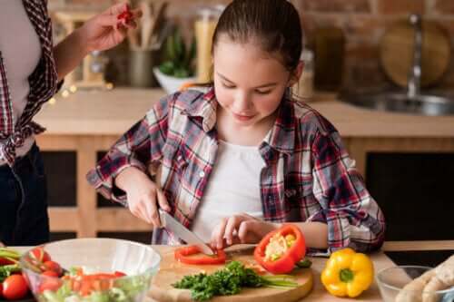 Kind helpt met koken door de groenten te snijden