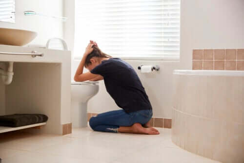 Een vrouw die overgeeft in het toilet vanwege Hyperemesis gravidarum